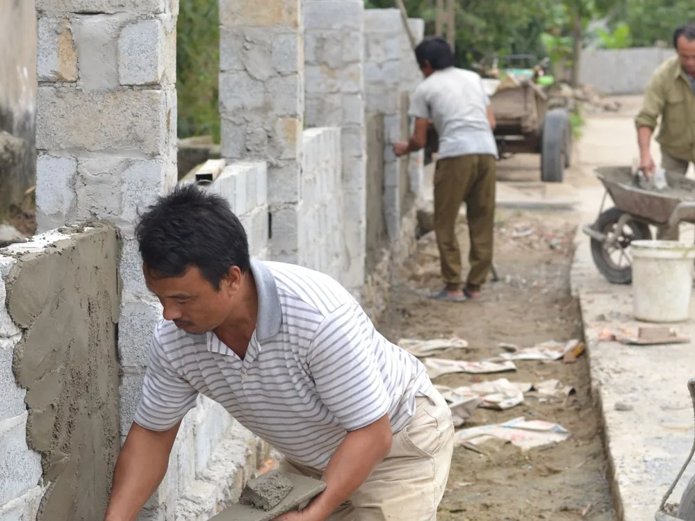 Maçons construisant un mur en parpaings et pierre sur un chantier extérieur