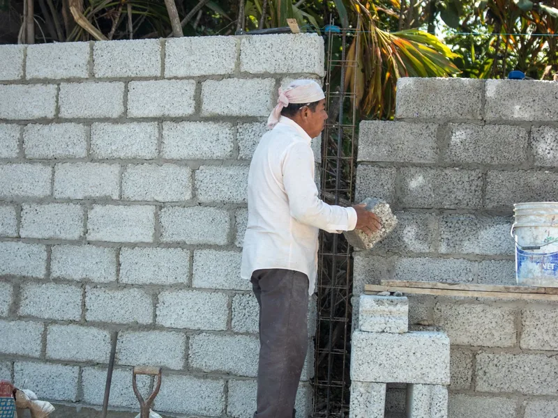Maçon montant un mur en parpaings dans un jardin